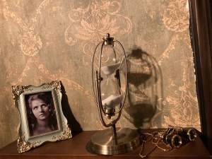 In-game: A photo of an actress, an hourglass, and opera glasses on a shelf.