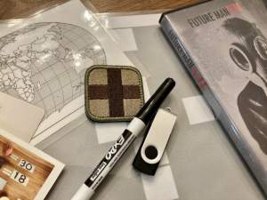 Assorted components including, a dry erase marker, a thumb drive, a world map, and a DVD labeled "Future Man"