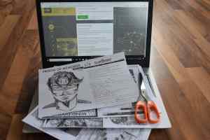 An assortment of printed components, a scissor, and a laptop.