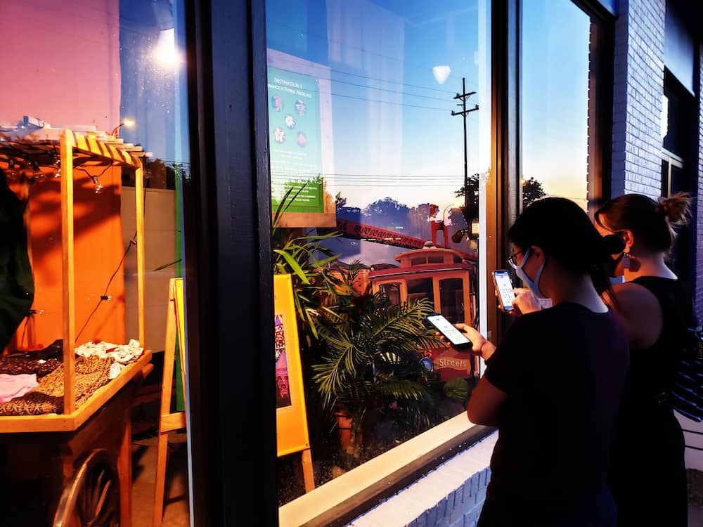 Two people on their phones in front of a window display.