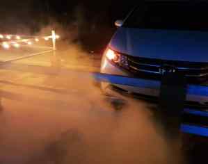 A parked car surrounded by lights and artificial fog.