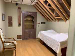 In-game: an attic with exposed beams, and assorted objects covered in sheets.