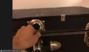 Hands opening a locked trunk viewed through Zoom.