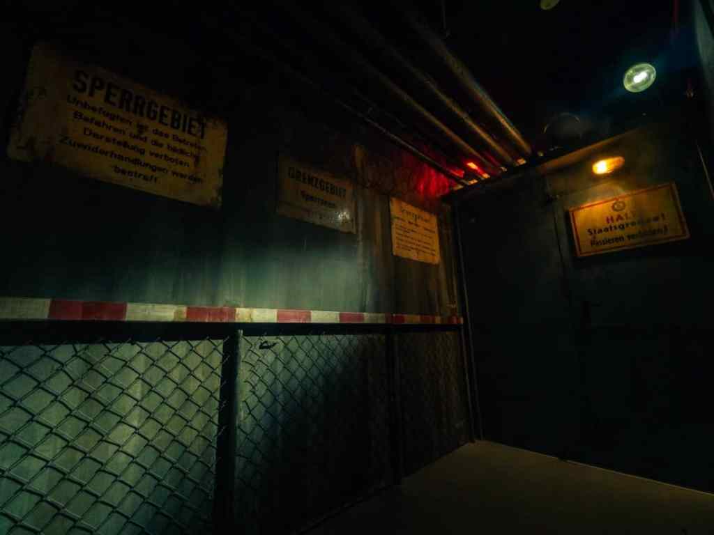 dark room with german signs on the wall and chain link fencing