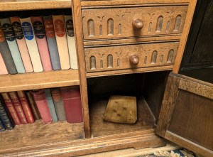 Closeup of an old desk, with an open cabinet and a puzzle within.