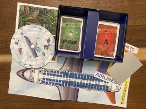 Assorted game components includes a seating chart for an airliner, riddle and help cards, a solution wheel, and a mirror.