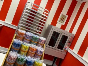Assortment of candy canes on display in a candy shop. An oven in the background.