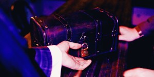 A hand reaching out for a small chest secured with a padlock.