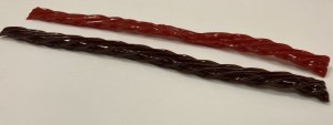 A brownish mystery flavor Twizzler beside a classic Twizzler.