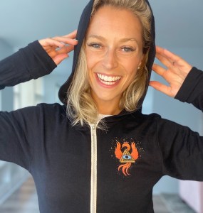 Woman wearing a black zipup hoodie with the RECON 21 phoenix and a hidden message.