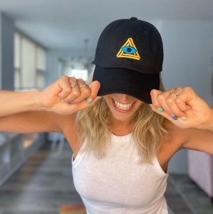 Woman wearing a black baseball cap with the RECON logo.