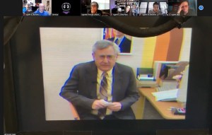 An older man sitting at a desk. It looks like a screenshot from grainy old video.