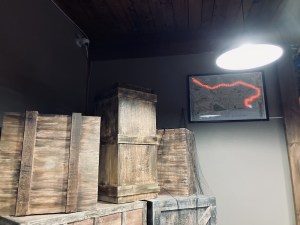 Warehouse area with a lot of large wooden crates and a map with a glowing train line path.