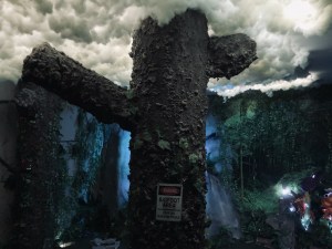 A large tree with ivy, the treetop surrounded by clouds in a forrest.