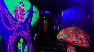 Blacklight illuminated Alice in Wonderland set with a glowing mushroom and Cheshire Cat.