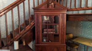 Close up of a display with books, a clock, and other trinkets behind glass.