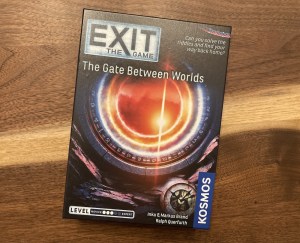 Exit The Game: The Gate Between Worlds box art has an orange portal set in a circular stone with symbols along the inner edge.