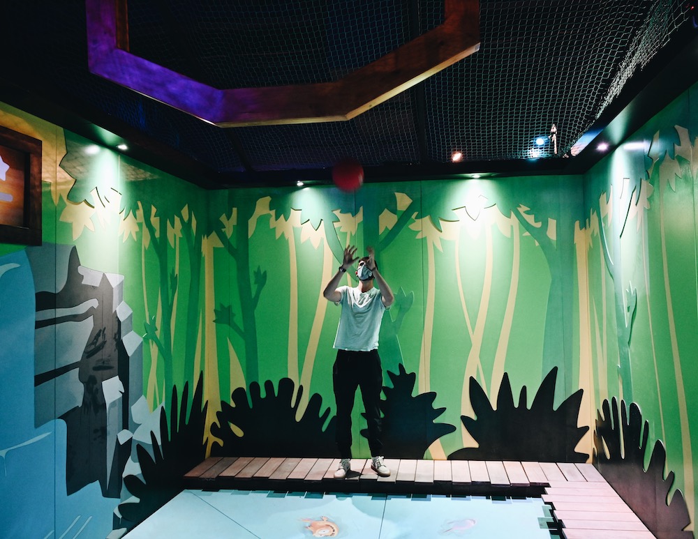 A player catching ball being thrown through a large ring over a pit in a painted rainforest environment. .