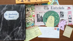 Vandermist Dossier box beside an assortment of interesting components, including a map, a newspaper and a strange spiral device.