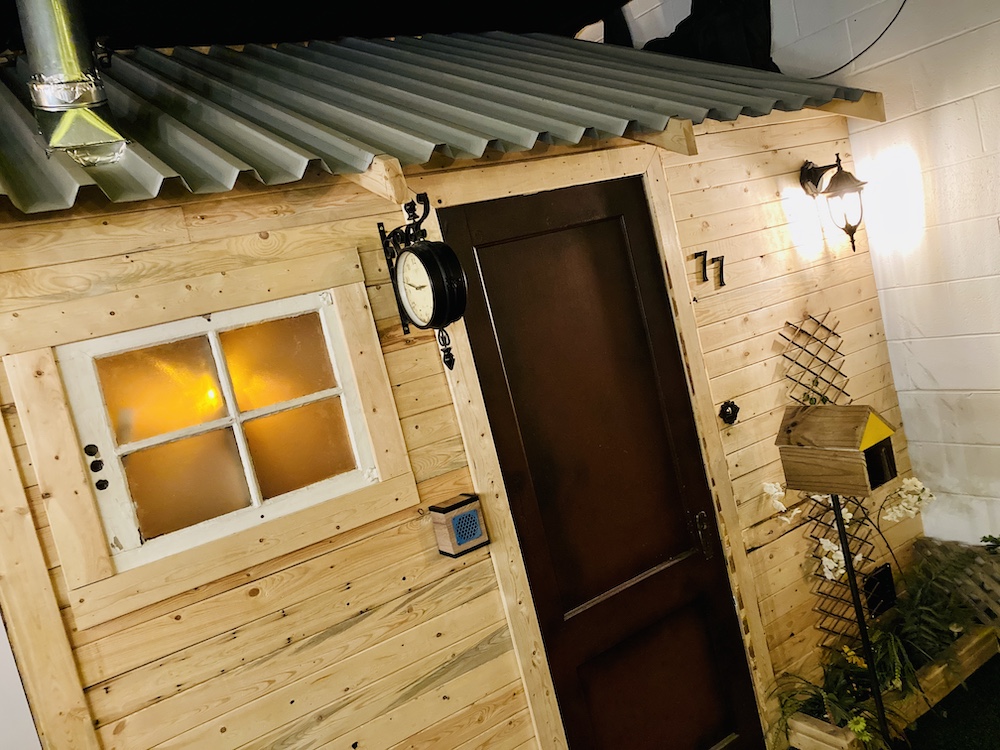 A small wood house with an aluminum roof, and a very cute mailbox.