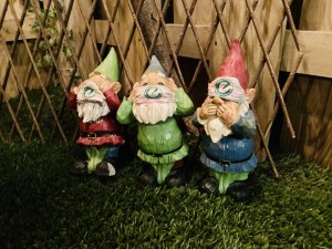Closeup of 3 see no evil, speak no evil, hear no evil garden gnomes .