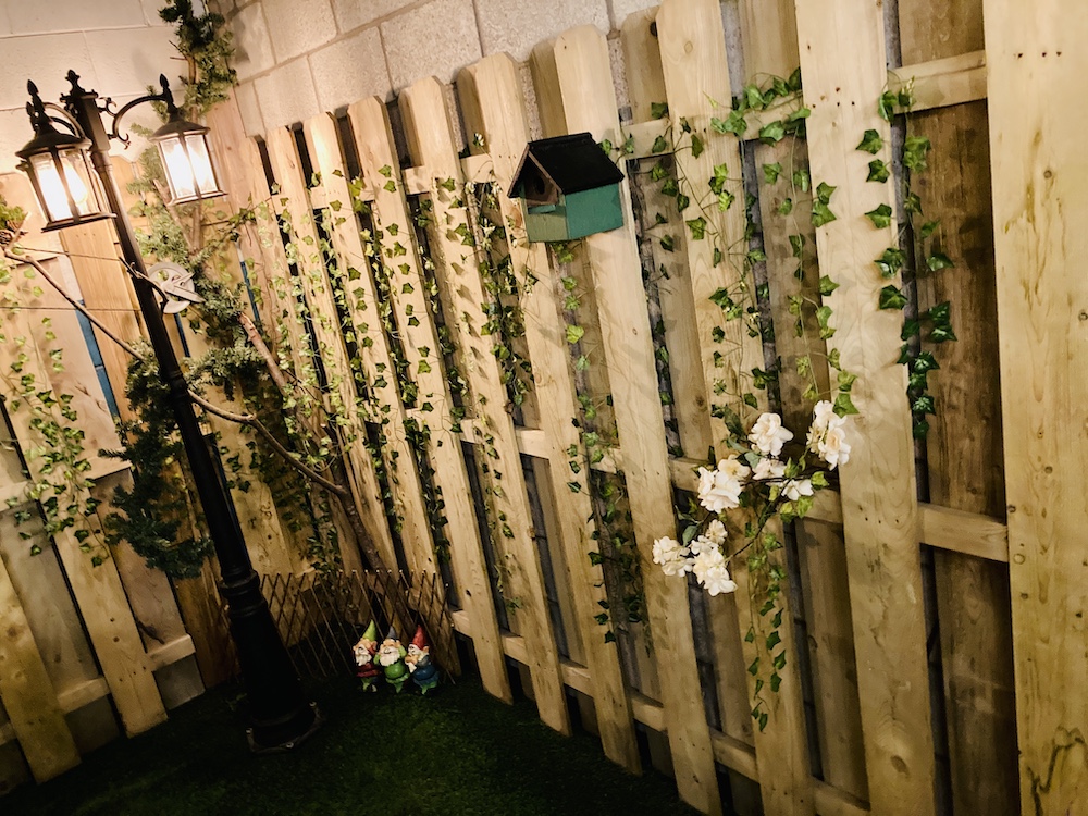 A wooden fence with some ivy and a birdhouse on it.