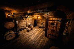 Wide view of a wooden pirate ship filled with barrels and other supplies.
