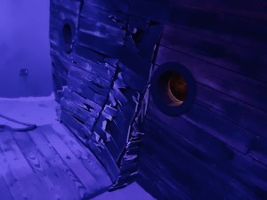 A ship at the bottom of the ocean, the hull is based in and heavily damaged.