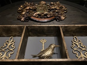 A shelf with a golden raven beside a golden key.