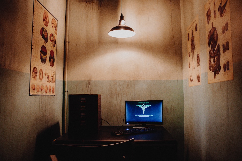 A computer in a small office surrounded by diagrams of human organ systems.