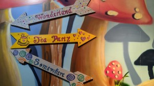 A collection of 3 signs with arrows, thy read, "wonderland," "tea party," and "somewhere."