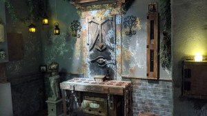 A table in front of a strange wooden wall carving in an old building.