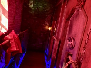 A red lit steampunk submarine exterior beside a wooden dock.