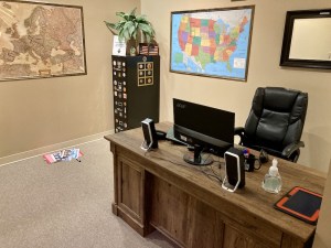 A desk with a computer in a travel agency. Maps are on the wall, and some papers are on the floor.