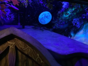 A full moon seen over a fairy house in the forest.