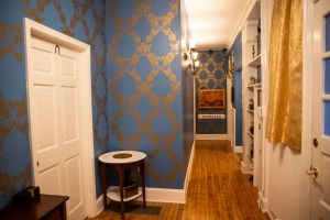 A hallway in a manner. The walls are painted blue with gold accents.