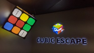 A rubik's cube logo for Cubic Escape, beside a large 3d rubik's cube.