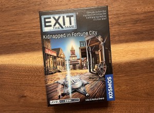 Exit: Kidnapped in Fortune City box depicts the old west. A sheriff's badge laying on the ground.