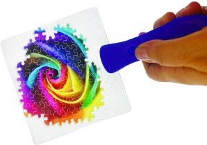 A handle with a large rectangular magnifier on the end over a collection of assembled puzzle pieces.