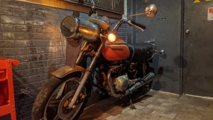 An old motorcycle beside a grey brick wall.