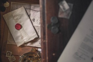 A sealed letter beside a sextant, a map, and some old coins.