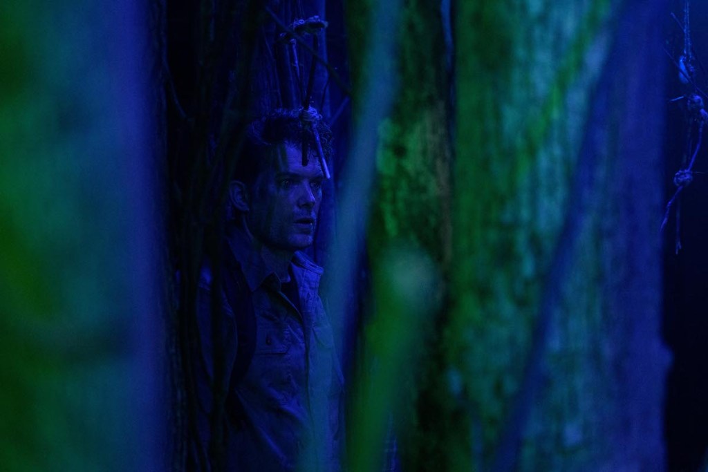 A man in the woods looking scared.