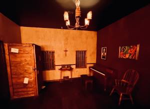 A dim room with a piano and a large box in the corner.