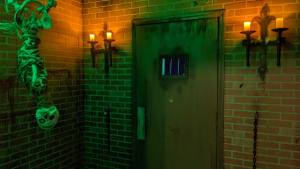 A skeleton hanging beside a large metal door with bars.