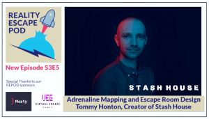 man with a shaved head in a denim button down shirt against a blue background