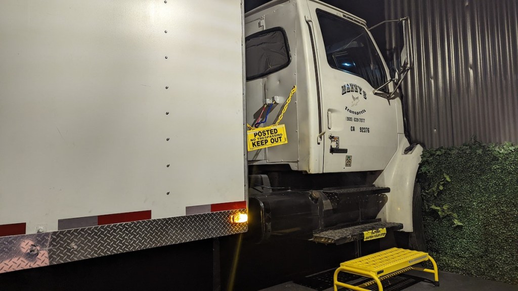 A large white truck that has crashed into the side of a building.