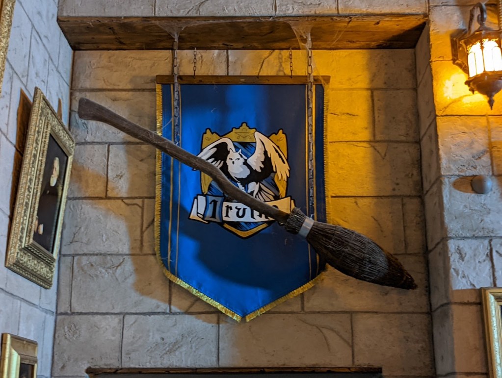 A house banner beside a brook hanging against a stone wall in a magic school.