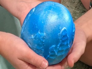 Small hands holding a blue egg.