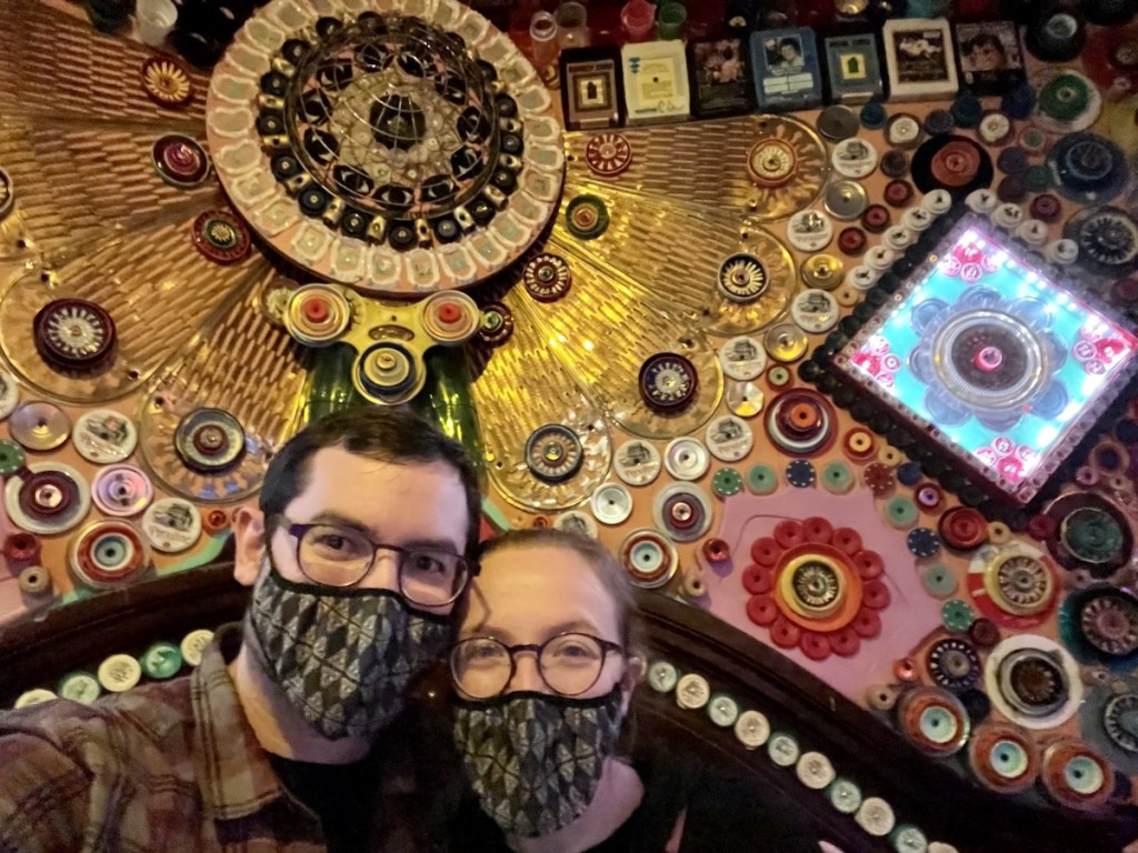Lisa and David in a strange room decorated beautifully by lots of tiny, random objects.