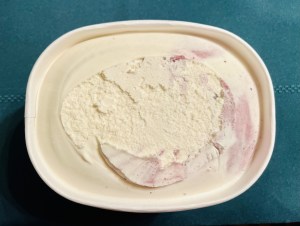 An open tub of Mystery Flavor Ice Cream, it looks white with purple inclusions.